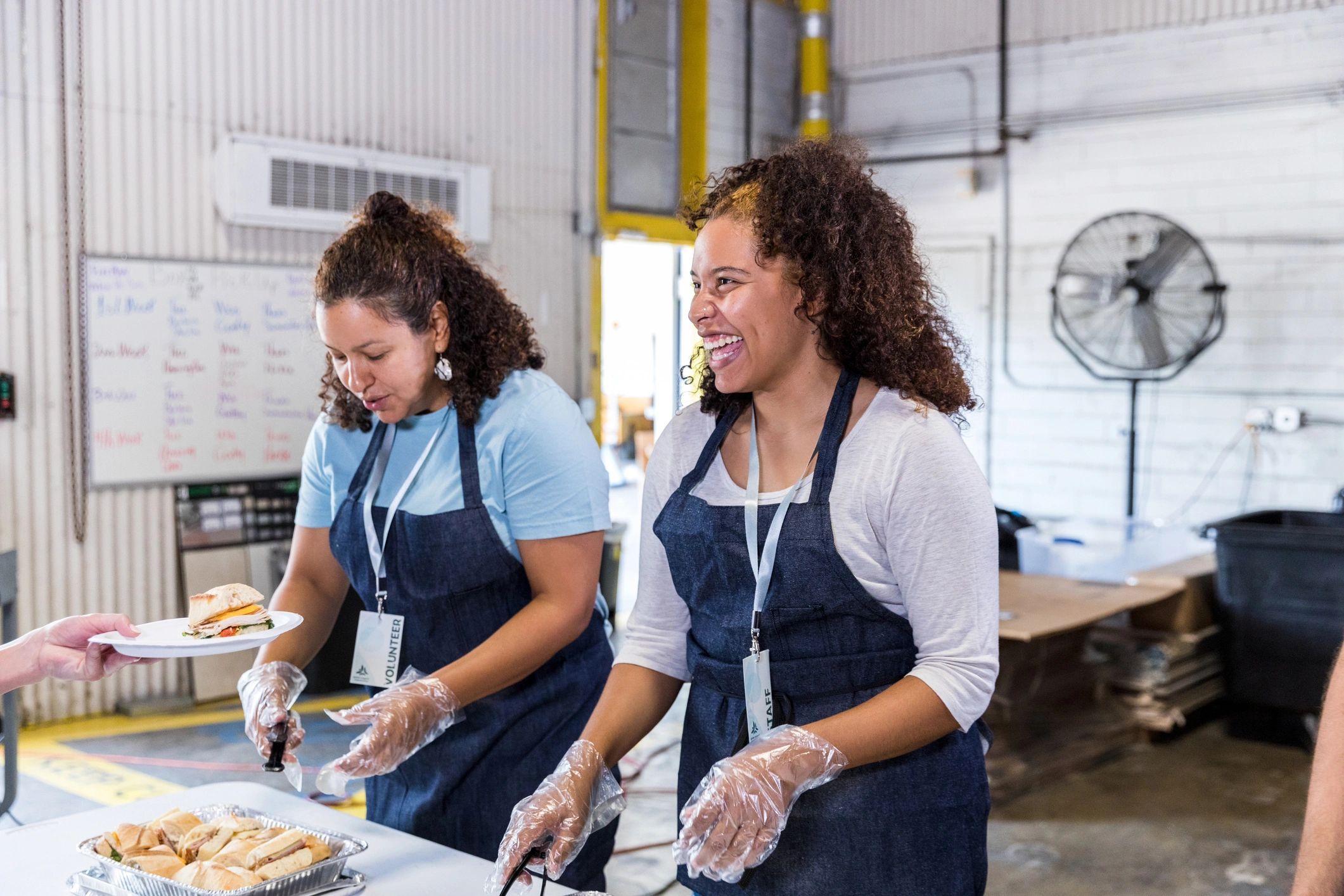 Female volunteers serving sandwiches to people in need